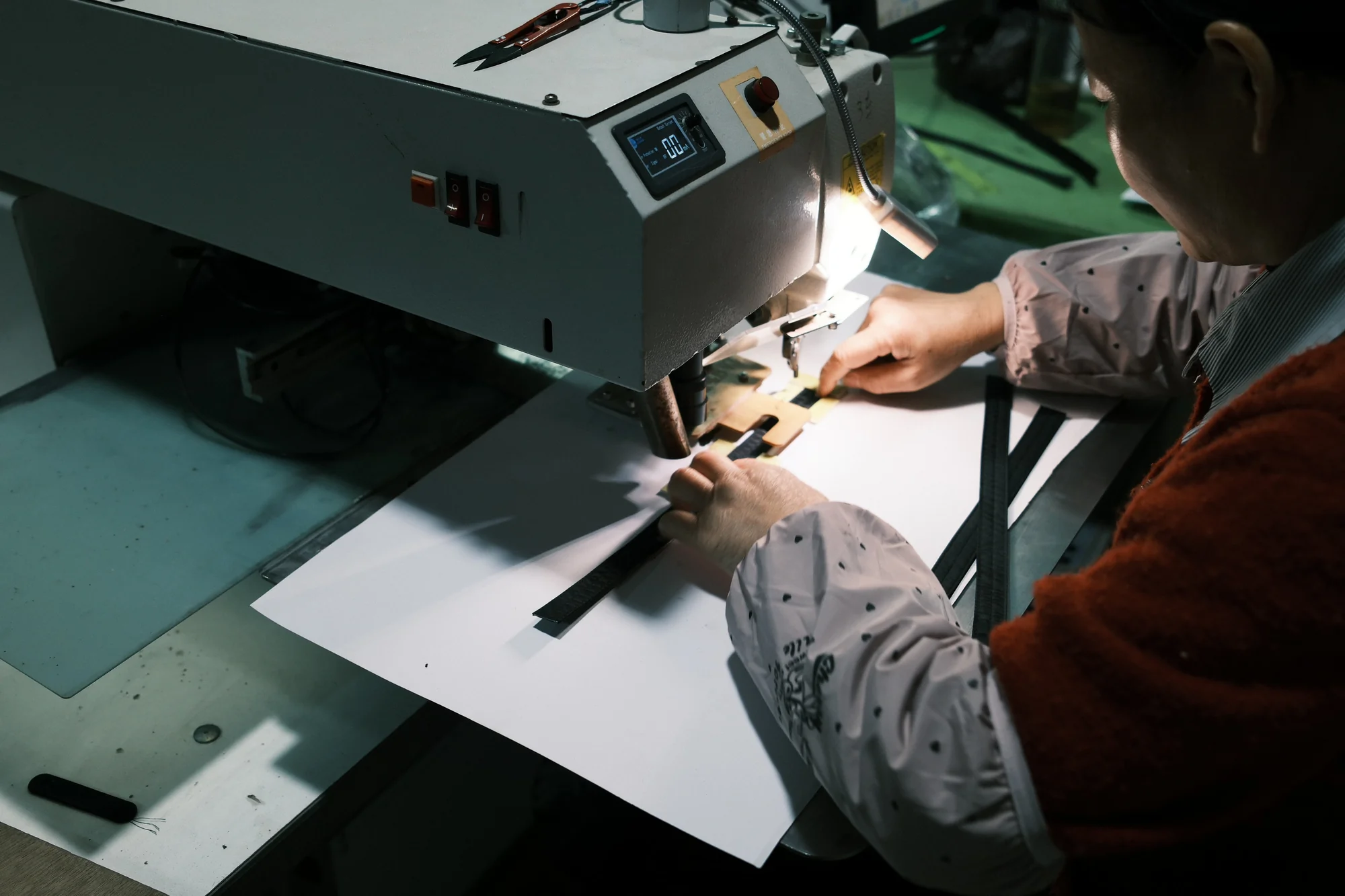 Operator at a sewing station finishing webbing detail